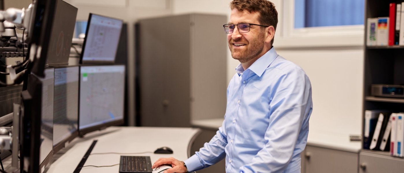 Person am Schreibtisch stehend und auf Bildschirme schauend